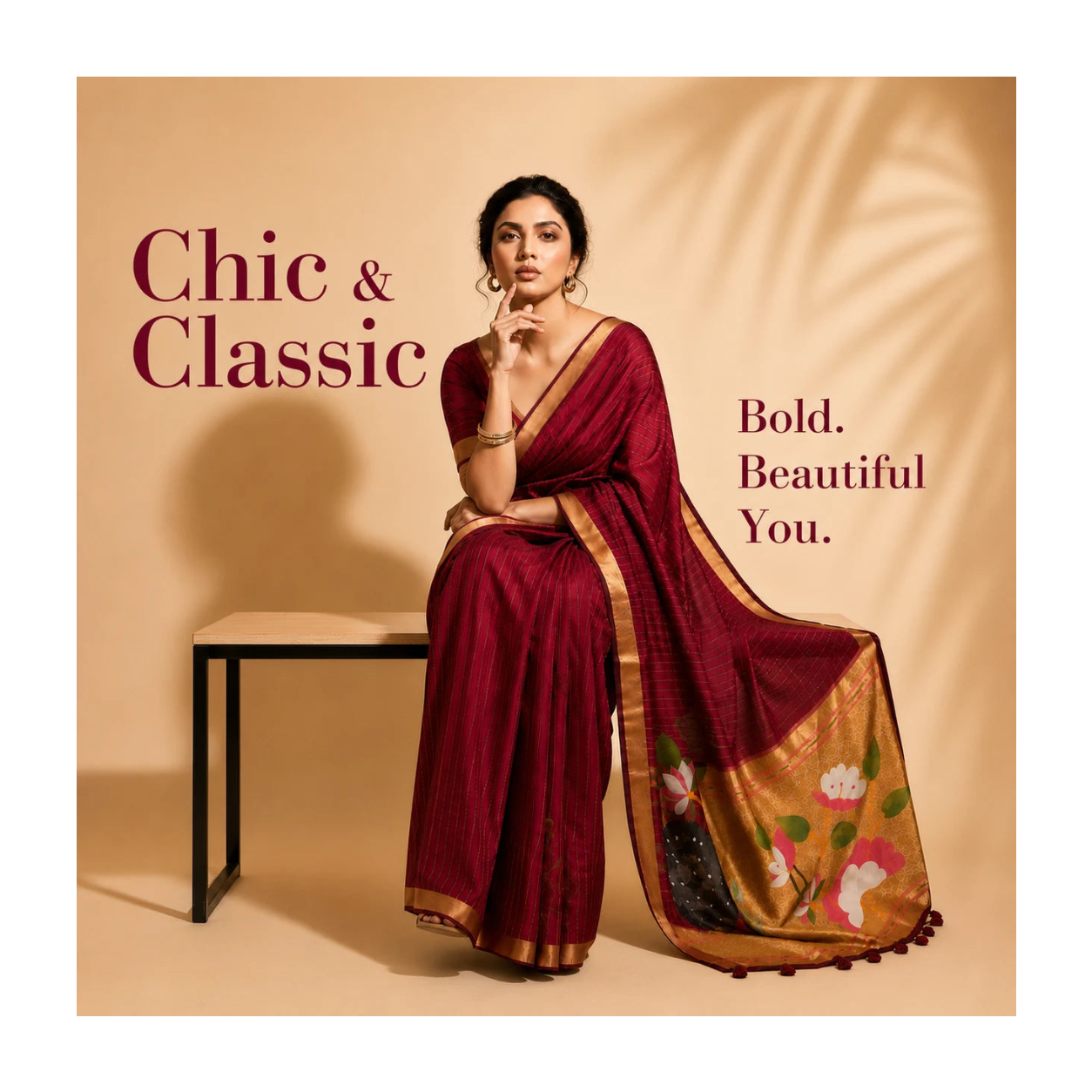 A woman wearing a deep maroon saree with gold borders and floral motifs on the pallu, seated on a minimalist black bench against a warm beige background with decorative shadows. Text on the image reads 'Chic & Classic' and 'Bold.